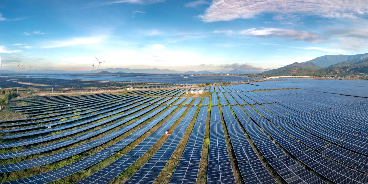 Expansive solar farm and wind turbines harnessing renewable energy at sunrise, showcasing sustainable technology.