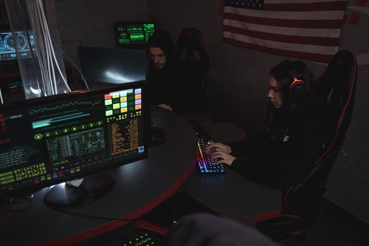 Cybersecurity professionals working on computer systems, focusing on data protection in a dimly lit room.